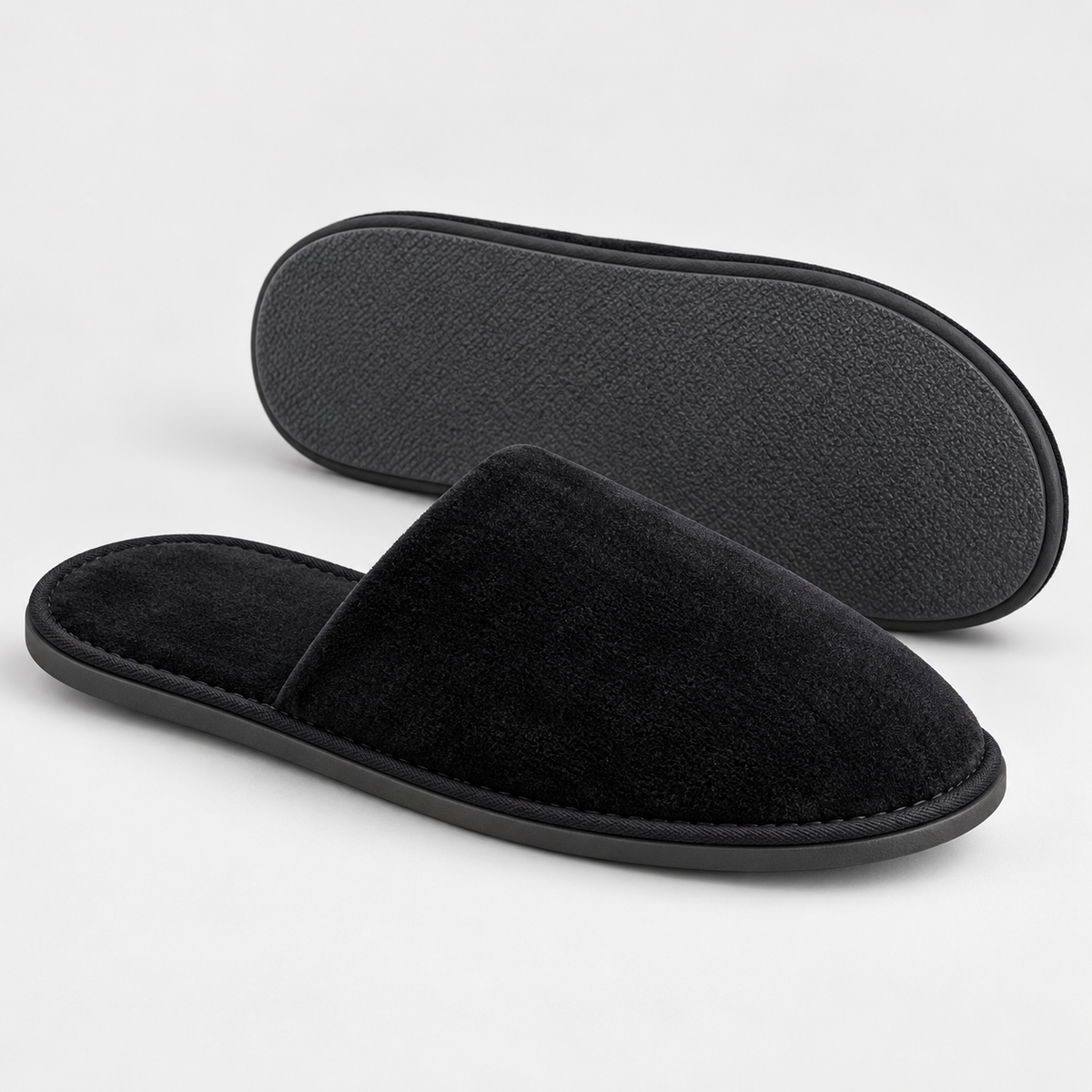 Side profile and outsole of black closed-toe velour hotel slippers