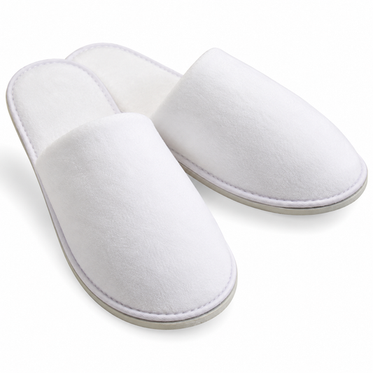 Pair of white closed-toe velour hotel slippers, three-quarter view