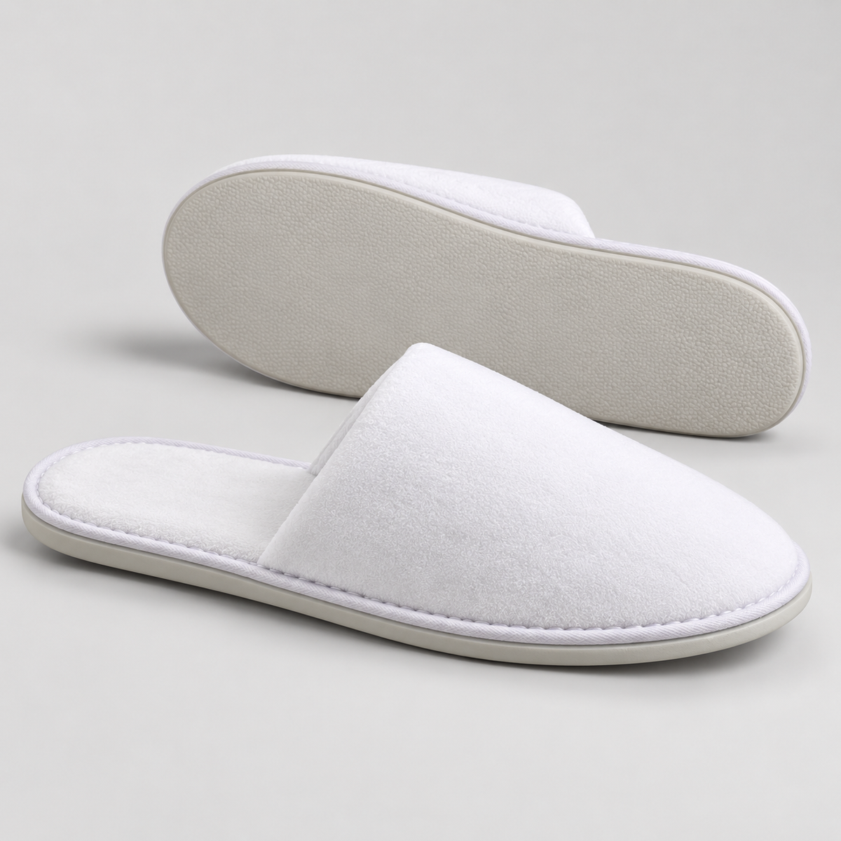 Side profile and outsole of white closed-toe velour hotel slippers