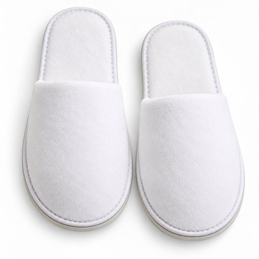 Overhead view of white closed-toe velour hotel slippers