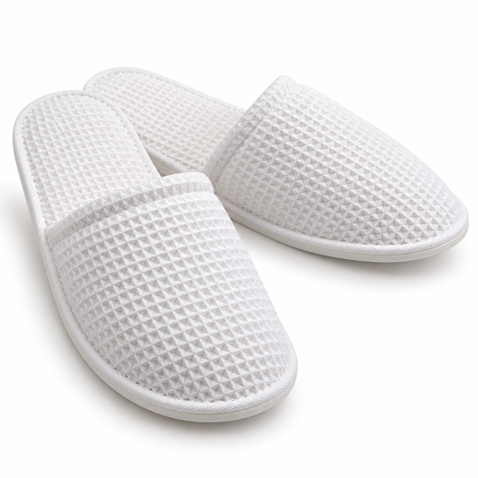 Pair of white closed-toe waffle hotel slippers, three-quarter view