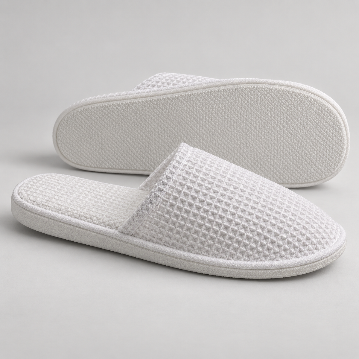 Side profile and outsole of white closed-toe waffle hotel slippers