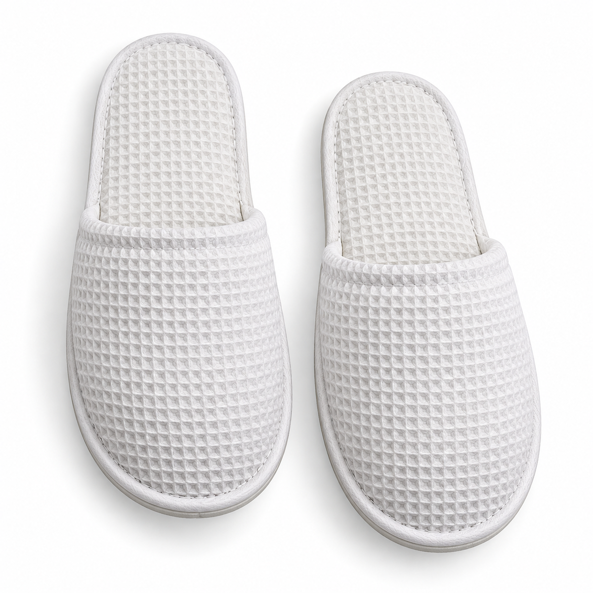 Overhead view of white closed-toe waffle hotel slippers