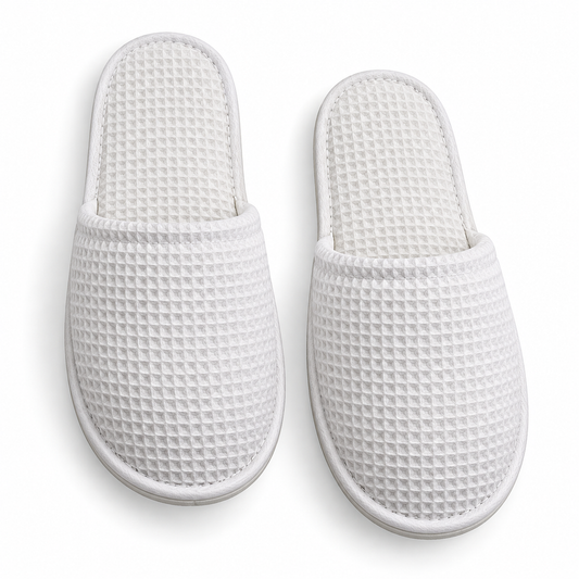 Overhead view of white closed-toe waffle hotel slippers
