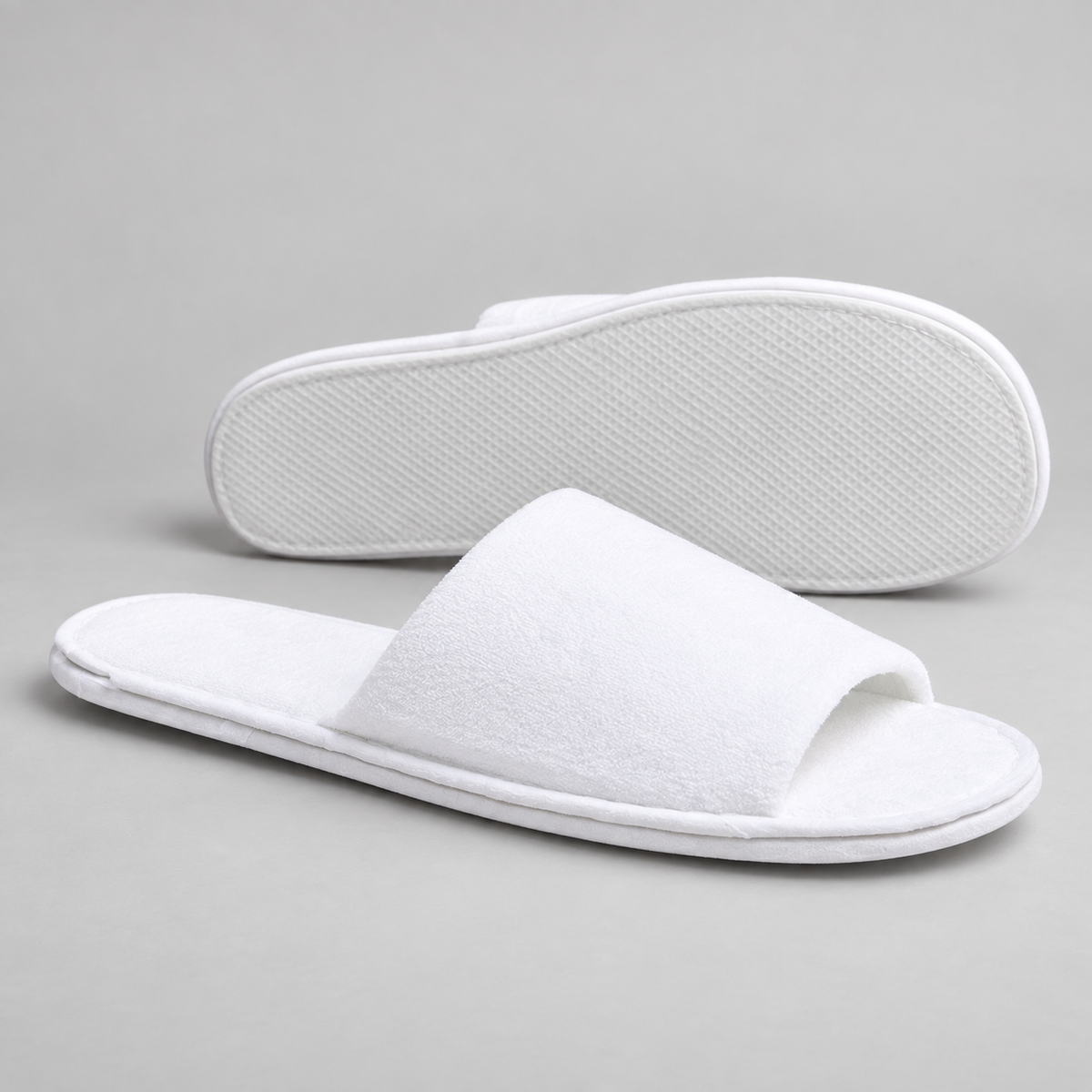 Side profile and outsole of white open-toe luxury hotel slippers